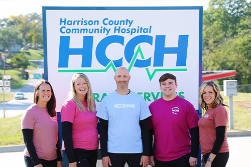 A group of HCCH employees in front of the hospital sign