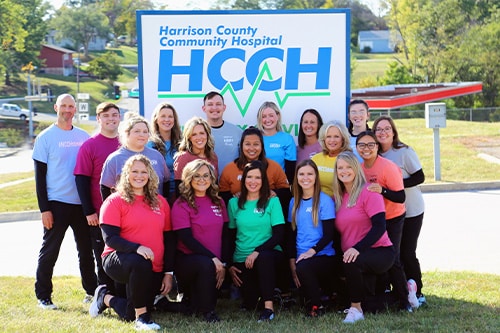 A group of HCCH employees in front of the hospital sign