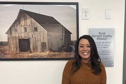 Photographer Lan Thompson poses next to her artwork at HCCH Medical Clinic.