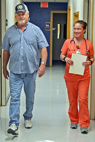 A pulmonary rehab patient and thier similing nurse walking down the hall of the hospital
