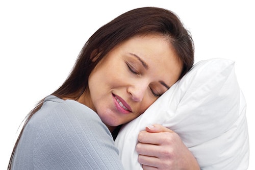 A woman hugging a pillow preparing to fall to sleep